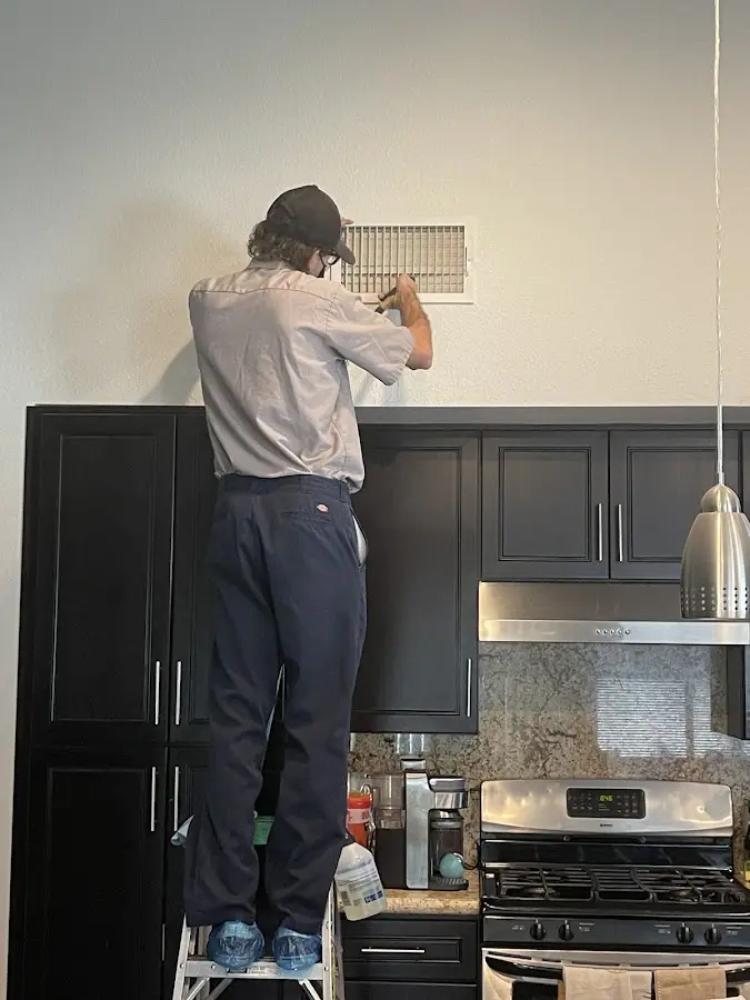 Technician inspecting an air vent during HVAC service in Pascagoula